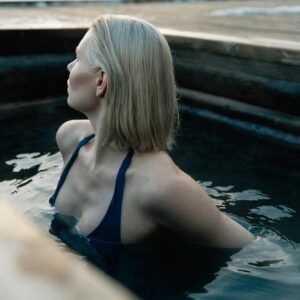 A young woman relaxes in a hot spring during winter with scenic mountain views.